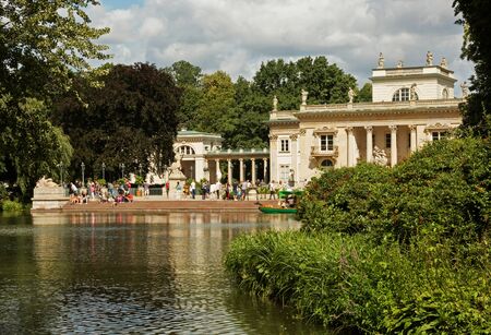 View on the pond,palace on the water (on island),tourist boat and many walkers in Lazienki Royal park in Warsaw.Beautiful ,sunny ,summer day. Editorial. Horizontal view.のeditorial素材