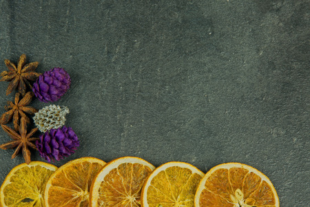 Christmas and New Yera decoration with dried slices of orange, star anise and colored cones with space for text on the right, an old stone, kitchen counter. Top, flat, horizontal view.の写真素材