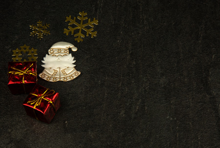 Christmas decoration with small packages,gold snowflakes and white Santa Claus on old, dark stone...