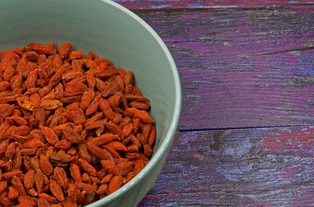 Ceramic bowl full of dry Goji berries on old wooden background in vintage style.Close , flat, horizontal view from above.の写真素材