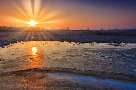 Sunrise over frozen fields and the reflection of the sun in the ice covering the field.Polska at the end of February.Horizontal view.の写真素材