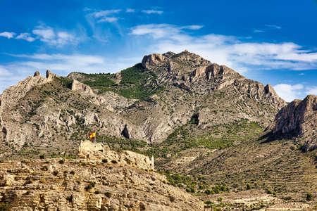 View of the hill with the ruins of the Busot castle and the Cabeco D'or mountains. Spain, Alicante provinceの写真素材