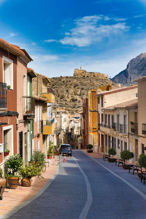 Busot in Spain, Alicante province. Historical, characteristically narrow street overlooking a hill with castle ruins. Vertical view.のeditorial素材