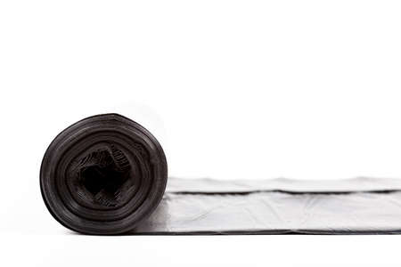 Single rolled out thick black roll of garbage bag isolated on white. Trash bag rolled out, generic home use household items, garbage disposal, plastics bad for the environment object studio shotの写真素材