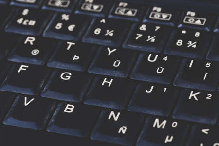 Old black dirty heavily used laptop notebook slightly dusty keyboard with special signs, matte shot,...