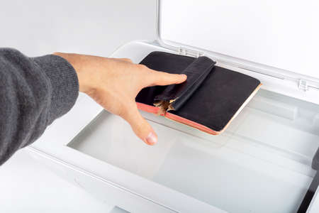 Man photocopying, scanning an old book on an open photocopier home printer Top view, hand placing a...