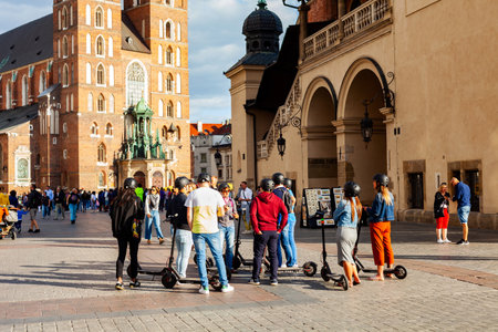 Cracow, MaÅopolska / Poland - circa December 2019: A group of people on electric scooters standing on the market square in front of St. Mary Basilica. Electric scooter usage in tourism, transportationのeditorial素材