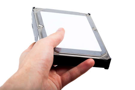 Hand holding and handing out a silver 3.5 inch HDD drive with an empty white blank sticker, label template, copy space. Hard drive, sharing data, giving away information abstract conceptの写真素材