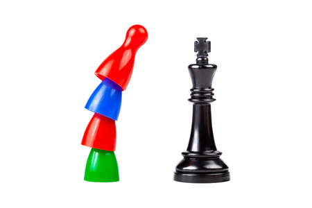 Teamwork against the ruler, revolution against authority. Traditional game pieces standing on top of each other in front, above a black king chess piece. Workers conflict of interests, inequalityの写真素材