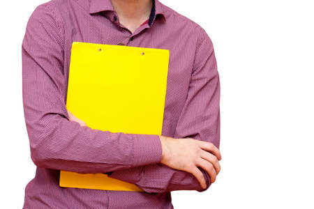 Young confident businessman or a student in a shirt with hands crossed holding an empty yellow paper holder isolated on white, copy space, confident pose, advertising or presenting an idea conceptの写真素材