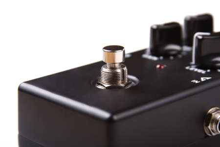 Blank black guitar effect pedal metal footswitch / button closeup, white background. Stompbox guitar...