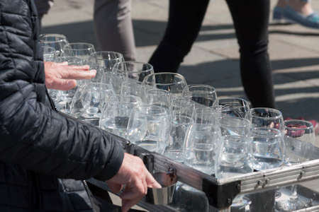 A busker, street performer, musician playing an unusual uncommon instrument made from wine glasses -...