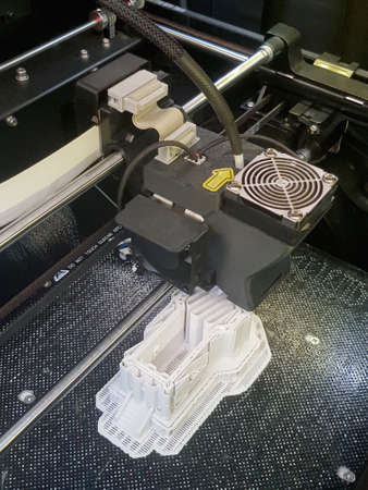 3D printer in action, printing of a complex white buliding model in progress, new future technology,...