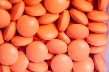 Lots of orange pills piling, extreme close-up.