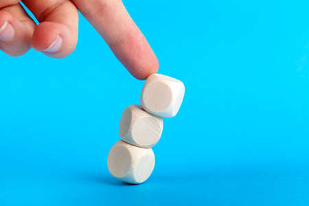 Structure collapsing, knocked over. Wooden cube tower pushed by human finger coming from above. Market collapse, crisis, lack of stability, breakdown and loss of balance abstract concept Cubes fallingの写真素材