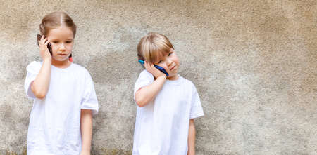 Sisters, two little girls, young children talking on their smartphones, kids speaking through their own modern mobile phones. Telecommunication, contact, cell phone usage, tech savvy kids conceptの写真素材