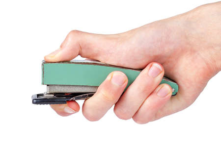 A big office stapler in hand, finger pressing the top part. Simple stapling gesture isolated on white background, cut out, closeup, side view. Using office tools and accessories conceptの写真素材