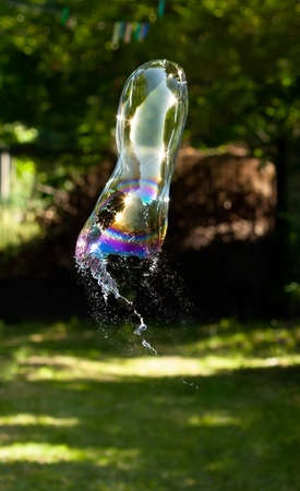 Single bursting soap bubble outside, high shutter speed. Bubble bursts outside in mid air, frozen motion. Failure, psychological stress, mental health strain abstract concept, nobody, green backgroundの写真素材