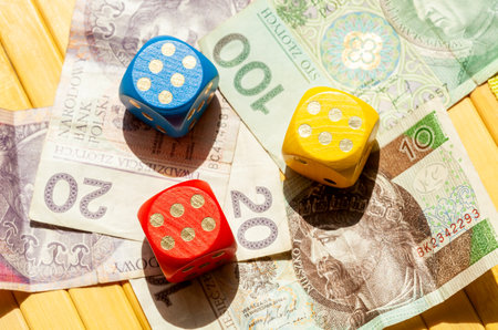 Three colorful game dice showing six laying on Polish zloty bills. Polish zÅ‚oty cash, banknotes...