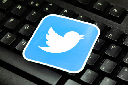 Twitter logo laying on a pc keyboard, closeup. Twitter bird square brand symbol on computer keys, detail. Tweeting, posting on Twitter, social media usage conceptのeditorial素材