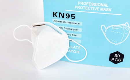 Single KN95 professional white protective medical face mask with filter beside a box, closeup, nobody. Simple new KN 95 anti viral mask container, bulk saleのeditorial素材