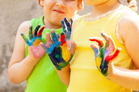 Two happy creative school age children, colorful painted hands, kids with hands covered in multi colored paint Arts and crafts, creativity, sensory integration, kids having fun, art education concept