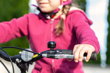 Little child, young school age cyclist riding a bike pressing the brake holding the handle bars, hands closeup. Kid sitting on a bicycle using the handbrake, braking and stopping, leisure, lifestyleの写真素材