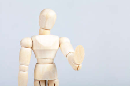 Wooden figurine, man doing a "stop it" hand gesture refusing something holding out a hand, refusal pose, rejection, psychology and body language simple abstract concept, single object closeup, nobodyの写真素材