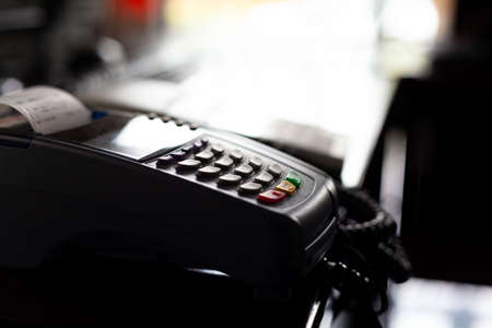 Pos Card payment terminal in the darkened shop, object detail, closeup, shallow dof, side view. Cashless payments terminal inside of a dark closed store, crisis, lockdown business concept, nobodyの写真素材