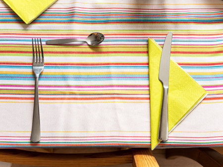 Cutlery on the table almost ready for the meal, objects top view, from above, closeup, nobody. Preparing the table concept, no plate, copy space in the middle. Fork, knife and a little spoonの写真素材