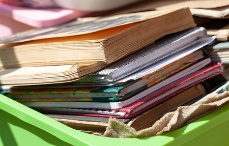 Lots of different old books and paper notebooks in a container outside in sunlight, stack. Box full of old literature, giving away used books. Book fairs, antiques, moving abstract concept, nobodyの写真素材