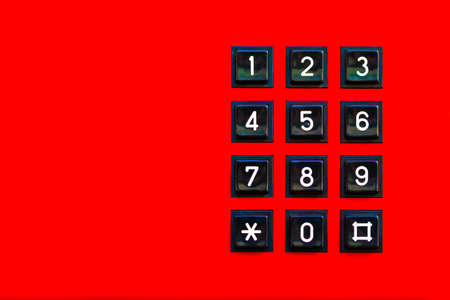 Simple red old classic retro landline phone keypad background, copy space. Vintage wired telephone number pad dial keyboard closeup, top view, from above. Red color, telecommunication abstract conceptの写真素材