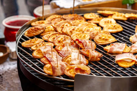 Traditional polish street food, sheep cheese, lots of smoked oscypki, delicious tasty oscypek with bacon on grill, sold on a local town market stall, local food culture conceptの写真素材