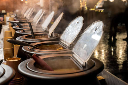 Hot open steaming pots full of many different delicious dishes, soups. Steam over food, preparing...