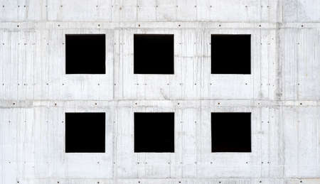 Six empty square windows, black window holes on a grey raw concrete wall, unfinished building side view, detail, frontal, front view, nobody. Building under construction abstract background, backdropの写真素材