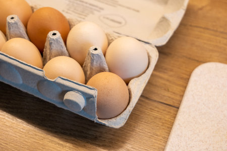 A pack of fresh eco free range farm eggs in the kitchen up close, detail shot, carton egg box container on a wooden table, closeup, nobody, no people Healthy eating, natural ingredients simple conceptの写真素材