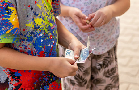 Two anonymous children holding Polish money, bills, banknotes and coins in hands closeup, detail. Kids receiving pocket money, monthly allowance simple concept, business, family finance managementの写真素材