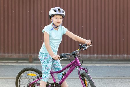 One happy young school age girl biker sitting on a bike smiling Cheerful cyclist kid on a bicycle, children sports leisure and recreation activities outdoors concept, copy space, one person, lifestyleの写真素材