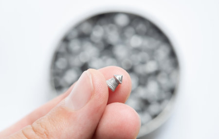 Man holding up one simple small metal air gun pellet, object macro, detail, extreme closeup. Air...