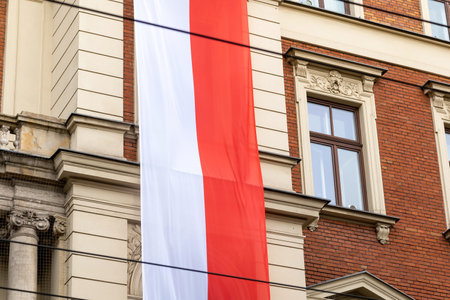 Large Polish flag hanging from the side of a building, Poland, Polish patriotism concept, national symbols, Independence Day parade. Object closeup, simple symbol, nobody, no peopleの写真素材