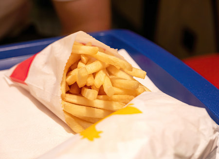 Salted fast food restaurant french fries and a burger laying on a table, object closeup, nobody,...