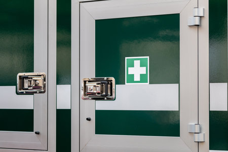 Mobile medkit compartment locked door on a vehicle with a green white cross symbol, professional first aid medical kit locker, treatment supplies, medicine, equipment container doors closeup, nobodyの写真素材