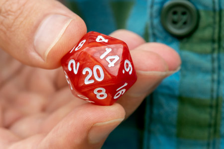 Hand holding a 20-sided d20 dice for RPG gaming, fingers closeup detail, one person, role-playing...