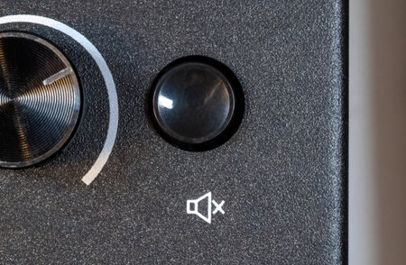 Close-up view of a simple mute button with a generic mute symbol on a simple audio device appliance,...