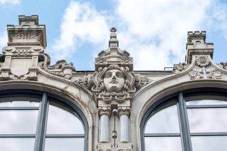 Closeup view of the architectural details on Polish Wroclaw historic Post Office building, showcasing sculptural elements and intricate stonework against a cloudy skyの写真素材