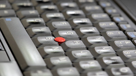 Laptop keyboard with a red track point in the middle, shallow depth of field closeup, computer keys background. Soft focus keys, writing, typing job abstract concept, nobody no people angle, side viewの写真素材