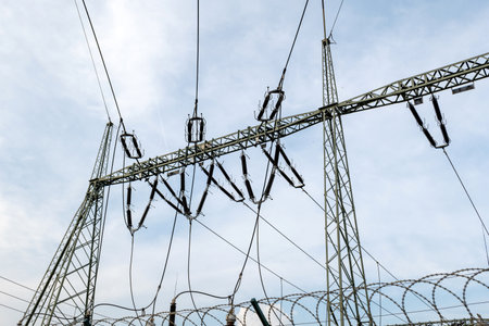 Electrical substation power station equipment towers on a cloudy sky background, detail shot,...