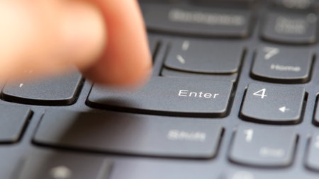 Man quickly pressing the enter key on a modern laptop computer keyboard, macro detail extreme closeup, shallow DOF, one person. Sending a message, buying, accepting rules, running a program conceptの写真素材