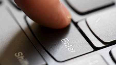 Man quickly pressing the enter key on a modern laptop computer keyboard, macro detail extreme closeup, shallow DOF, one person. Sending a message, buying, accepting rules, running a program conceptの写真素材