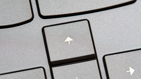 Up arrow key on a modern laptop computer keyboard, extreme closeup detail macro shot. Moving up and forward in corporate business, way ahead, front, going towards end goals symbol simple conceptの写真素材